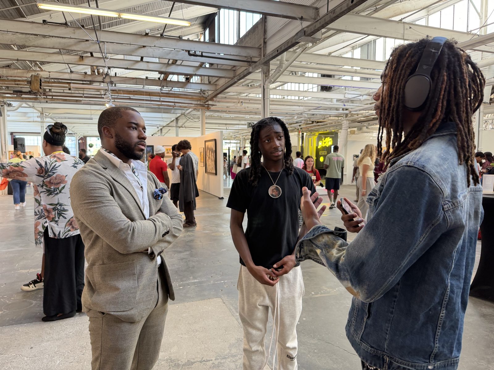 Donald Val listens as two young men talk during a community art exhibition