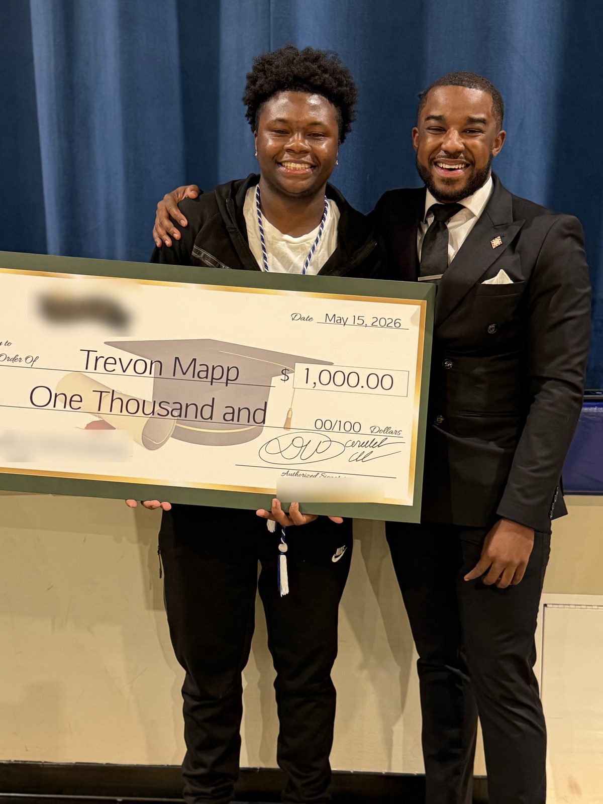 The graduate and presenter smile together with the scholarship check