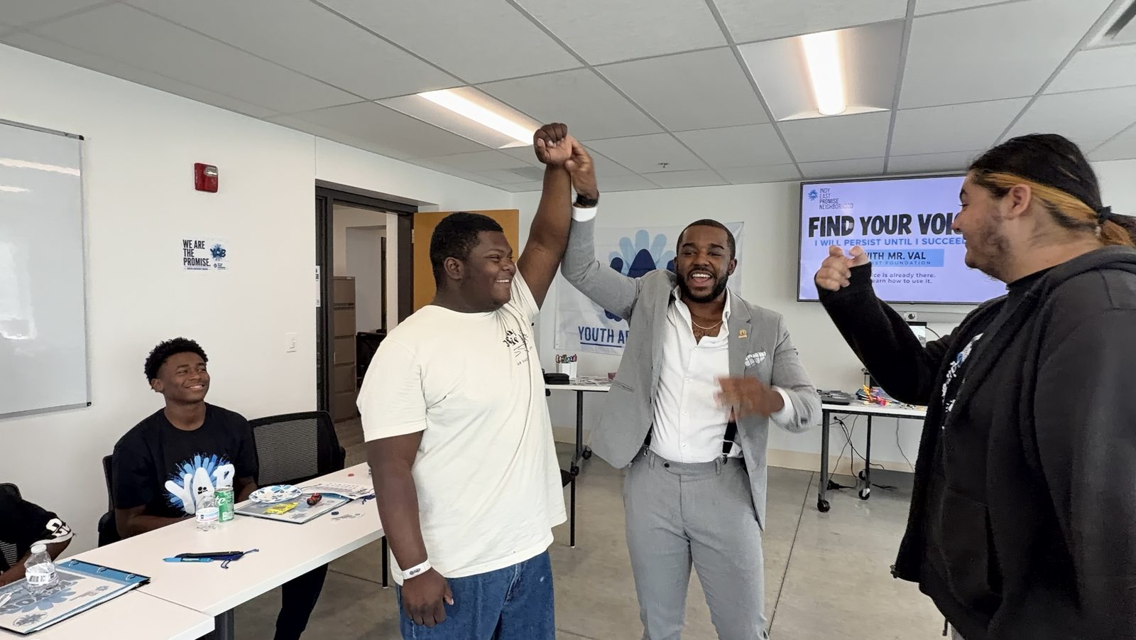 Donald Val raises a student’s arm in celebration during the Find Your Voice workshop as other students cheer